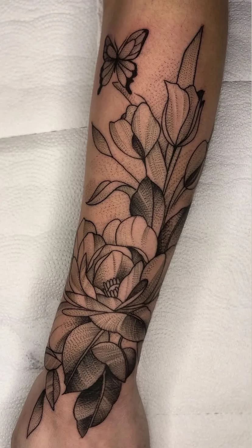 Tatuagem floral com borboleta em fine line no antebraço