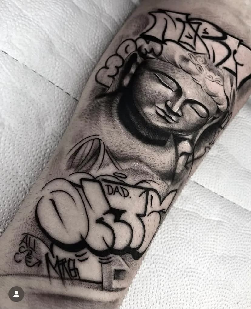 Tatuagem de Buda com elementos de graffiti em preto e cinza no antebraço