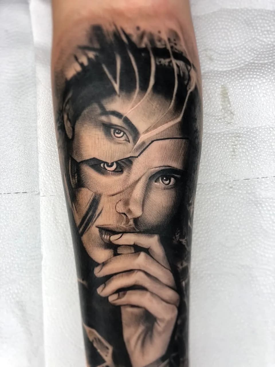 Tatuagem realista de rosto feminino abstrato em preto e cinza no antebraço